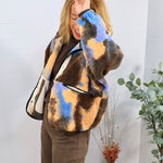 Woman wearing oversized brown blue and peach abstract sherpa jacket over chocolate turtleneck and brown trousers