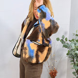 Woman wearing oversized brown blue and peach abstract sherpa jacket over chocolate turtleneck and brown trousers
