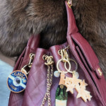 Burgundy quilted Chanel caviar leather bag with solar eclipse "Caviar Luxury" keychain, champagne bottle charm, and snowflake