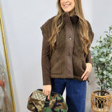 Woman wearing a chocolate brown teddy shearling vest over a brown long-sleeve top with wide-leg jeans