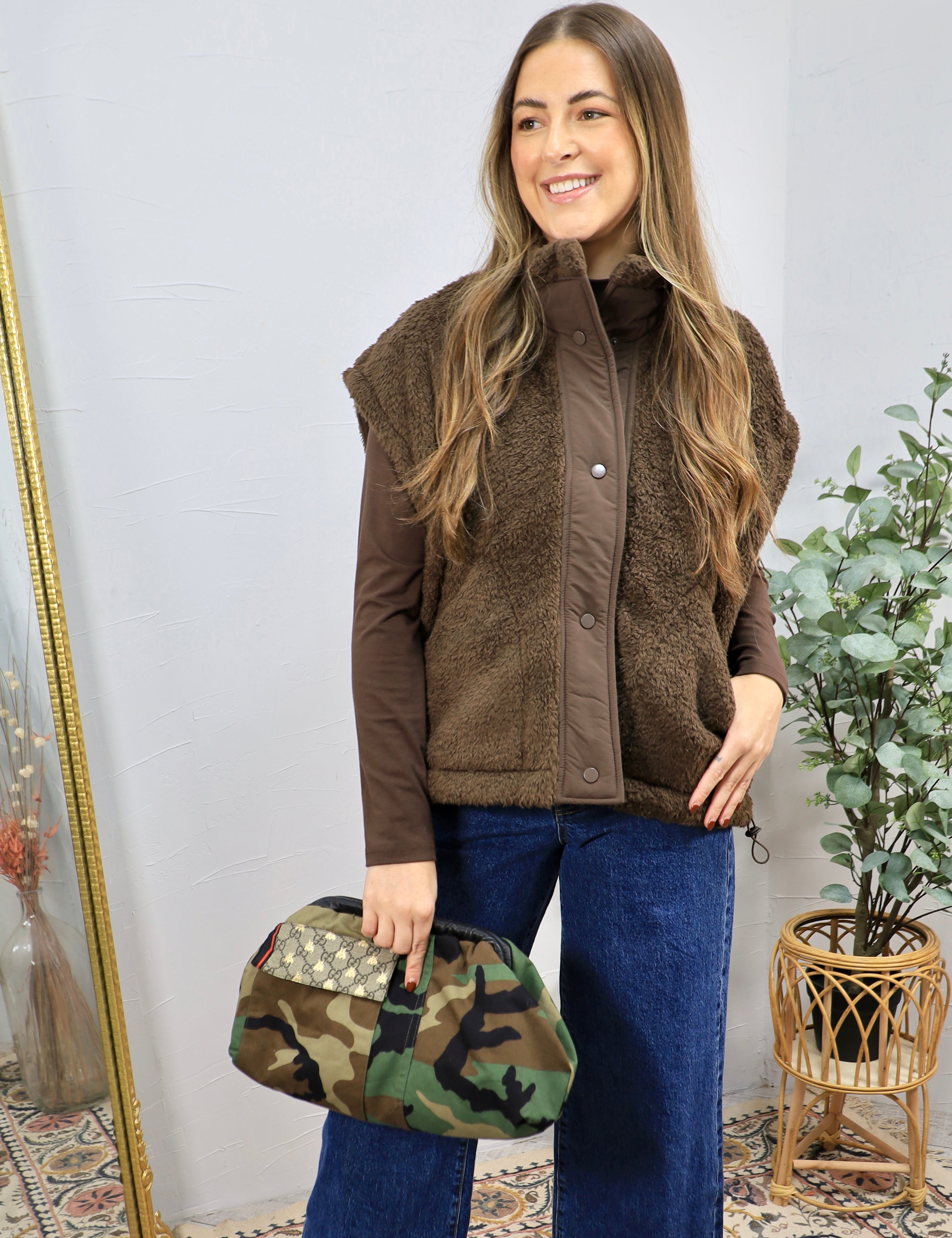 Woman wearing a chocolate brown teddy shearling vest over a brown long-sleeve top with wide-leg jeans