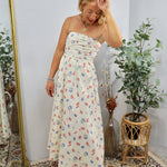 Woman wearing cream strapless midi dress with colorful floral print in styled room with plants