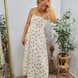 Woman wearing cream strapless midi dress with colorful floral print in styled room with plants