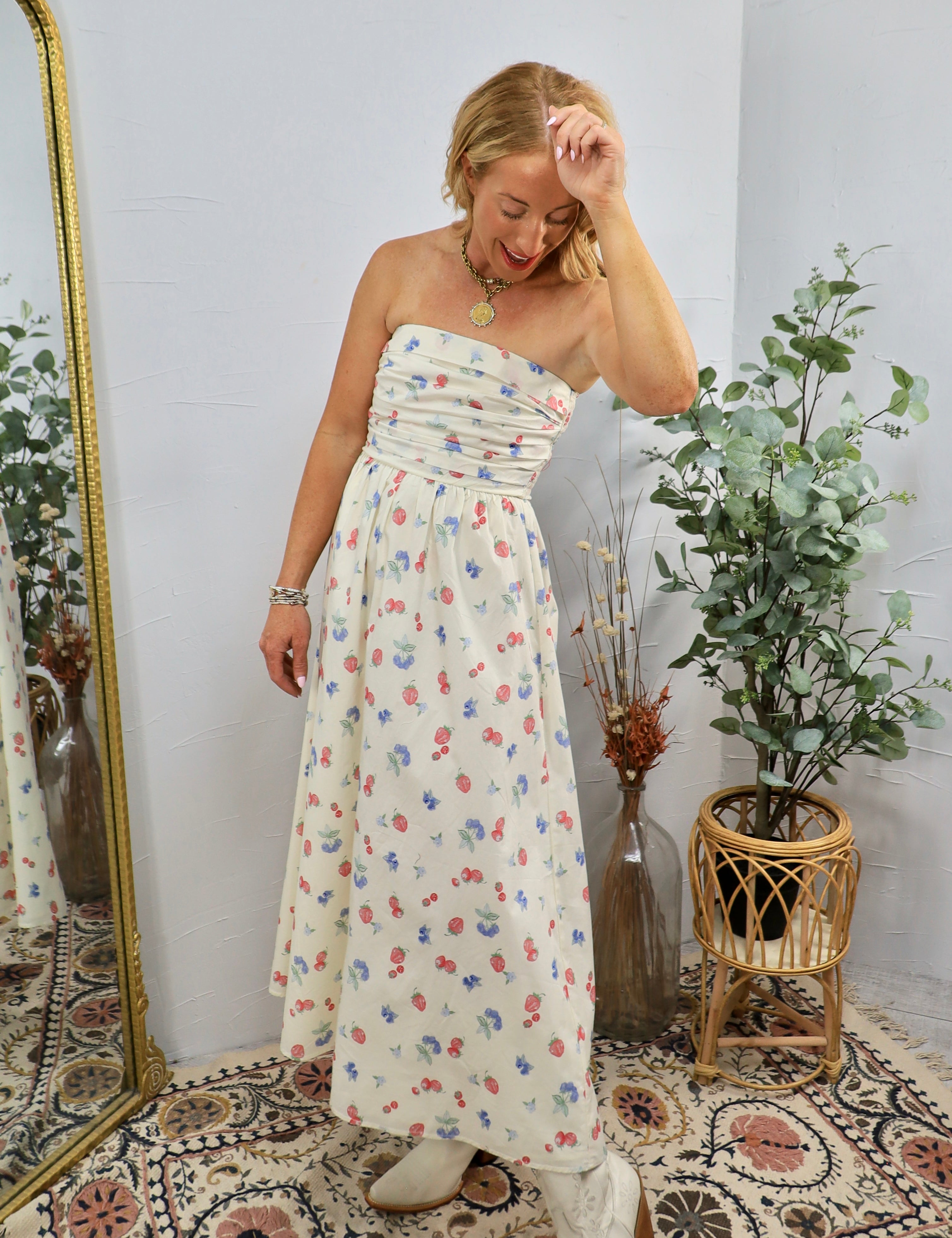 Woman wearing cream strapless midi dress with colorful floral print in styled room with plants