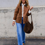 Woman wearing a caramel brown barn jacket with wide-leg jeans and a brown studded hobo bag