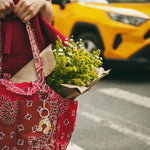 Red bandana paisley tote bag with Solar Eclipse keychain charm, styled with fresh wildflower bouquet and red outfit.