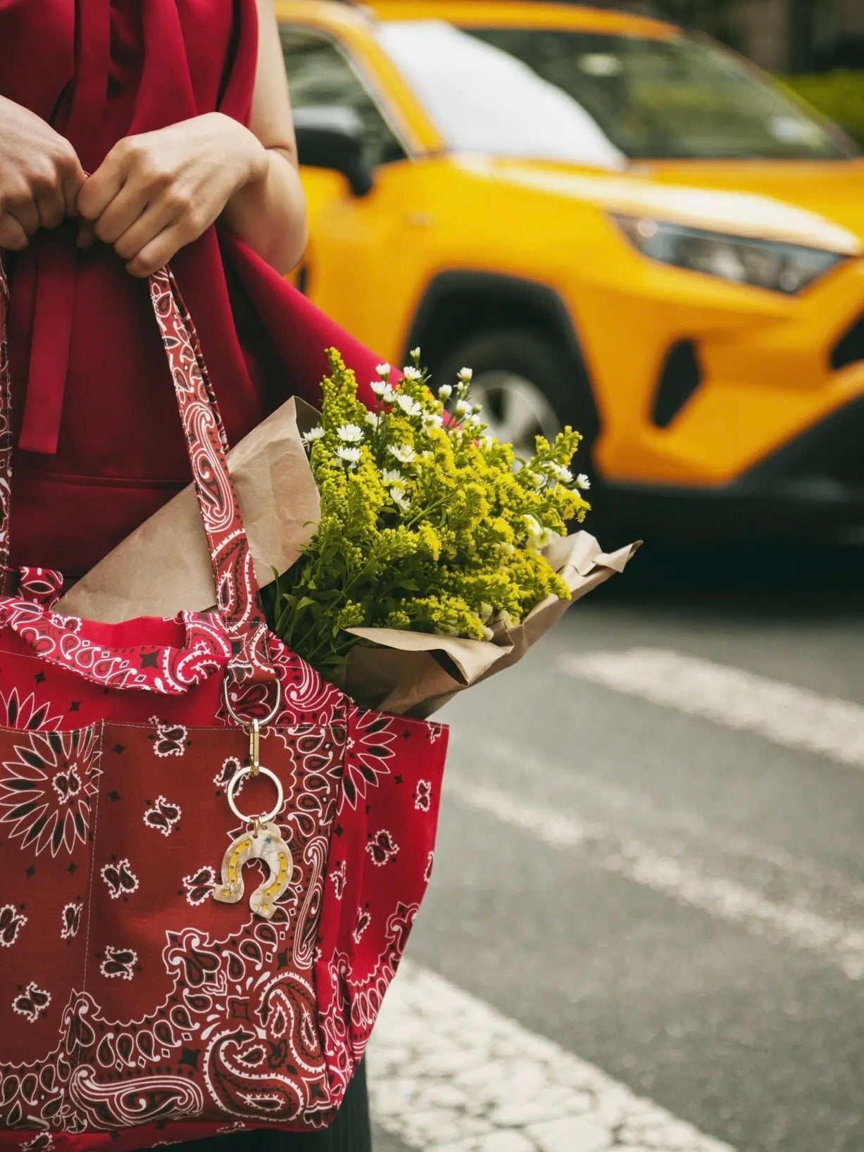 Red bandana paisley tote bag with Solar Eclipse keychain charm, styled with fresh wildflower bouquet and red outfit.