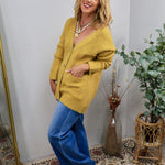 Oversized chartreuse yellow knit cardigan with front pockets, styled with wide-leg blue jeans and layered necklaces.