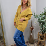 Oversized chartreuse yellow knit cardigan with front pockets, styled with wide-leg blue jeans and layered necklaces.