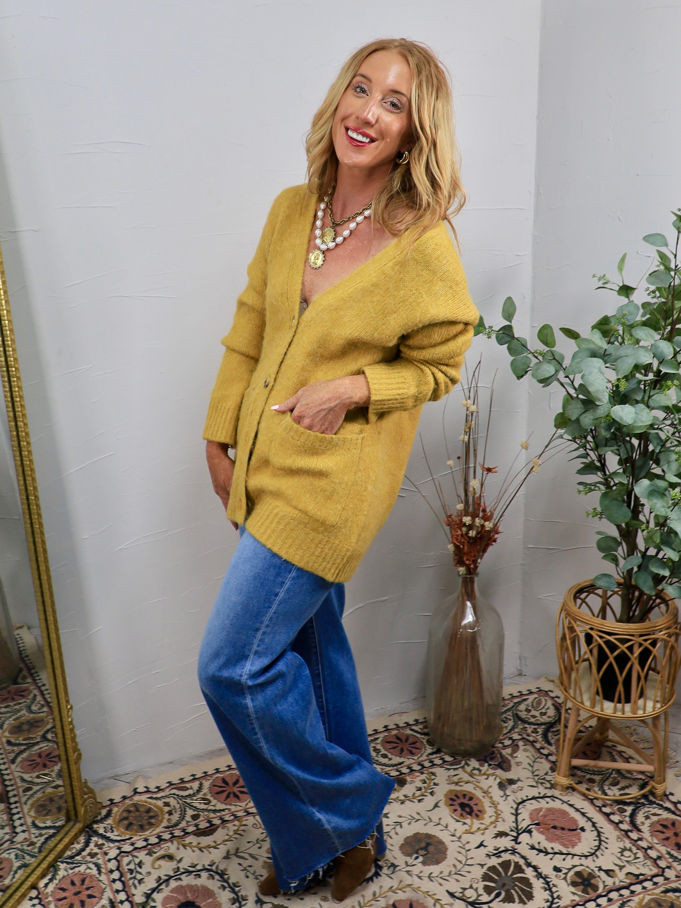 Oversized chartreuse yellow knit cardigan with front pockets, styled with wide-leg blue jeans and layered necklaces.
