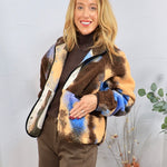 Multicolor sherpa jacket in brown, blue, and tan plaid, styled over brown turtleneck and trousers.