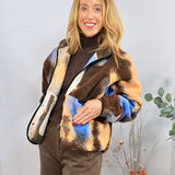 Multicolor sherpa jacket in brown, blue, and tan plaid, styled over brown turtleneck and trousers.