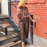 Rust brown printed chiffon tie-neck blouse with long sleeves, styled with chocolate leather culottes and tan boots.