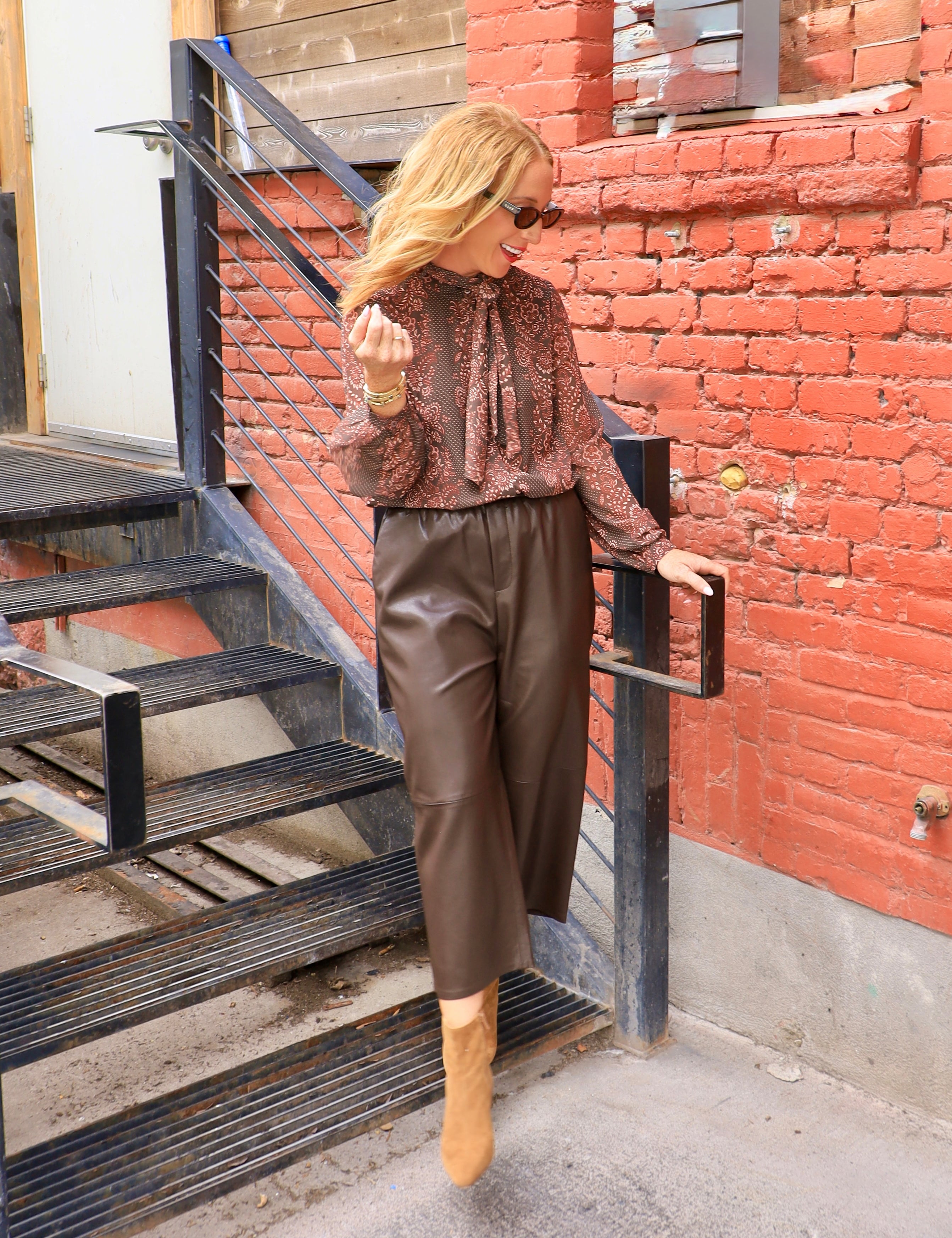 Rust brown printed chiffon tie-neck blouse with long sleeves, styled with chocolate leather culottes and tan boots.