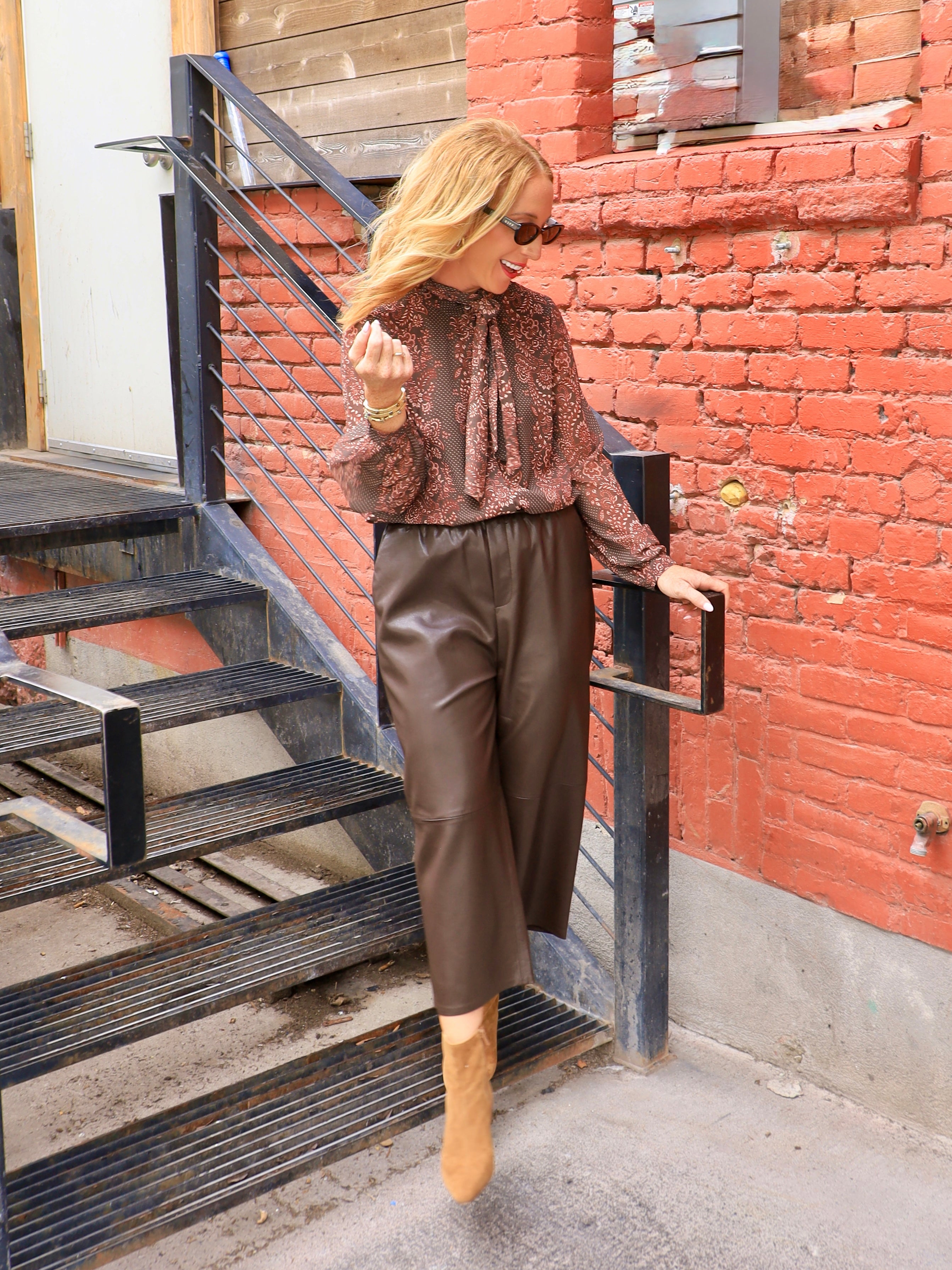 Rust brown printed chiffon tie-neck blouse with long sleeves, styled with chocolate leather culottes and tan boots.
