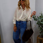 Woman wearing an ivory sheer button-front top with twist hem, paired with high-rise flare jeans