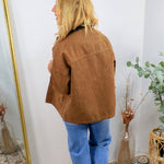 Brown acid-wash barn jacket with patch pockets, worn over blue jeans and dark collar shirt, back view.