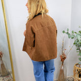Brown acid-wash barn jacket with patch pockets, worn over blue jeans and dark collar shirt, back view.