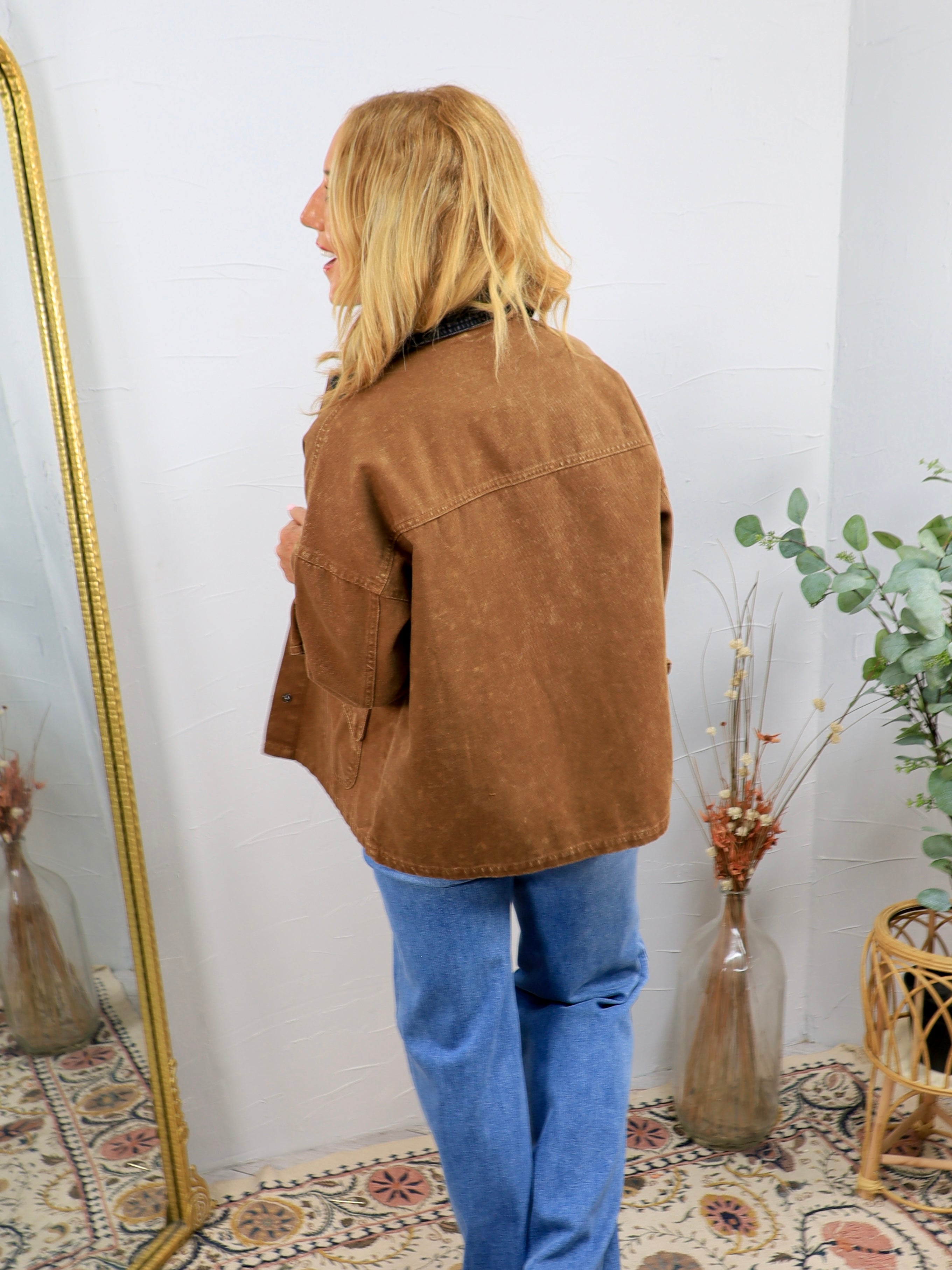Brown acid-wash barn jacket with patch pockets, worn over blue jeans and dark collar shirt, back view.
