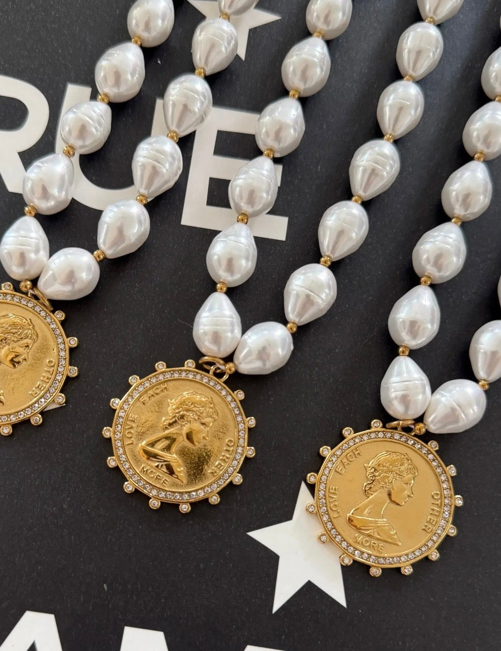 Pearl beaded necklaces with gold crystal-halo coin pendants engraved with Love Each Other More