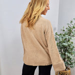 Beige knit crewneck sweater with ribbed hem and cuffs, styled with black pants, back view.