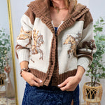 Woman wearing a cream and brown western horse-pattern knit cardigan sweater with ruffled hood and button front