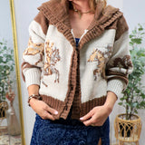 Woman wearing a cream and brown western horse-pattern knit cardigan sweater with ruffled hood and button front