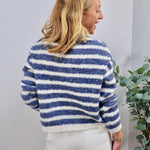 Blue and white striped fuzzy knit crewneck sweater shown from the back, paired with white pants.