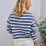 Blue and white striped fuzzy knit crewneck sweater shown from the back, paired with white pants.