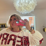 White crewneck sweatshirt with red plaid appliqué "MERRY" lettering, red ribbed collar trim, and balloon sleeves.