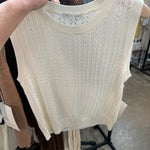 Ivory cable knit sleeveless tank top with pointelle pattern hanging on wooden hanger