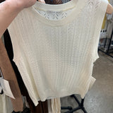 Ivory cable knit sleeveless tank top with pointelle pattern hanging on wooden hanger