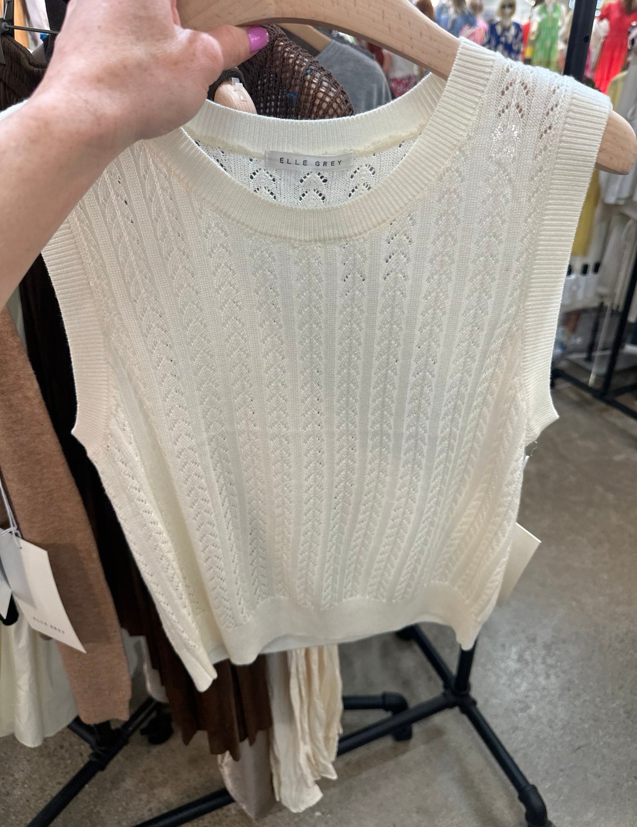Ivory cable knit sleeveless tank top with pointelle pattern hanging on wooden hanger