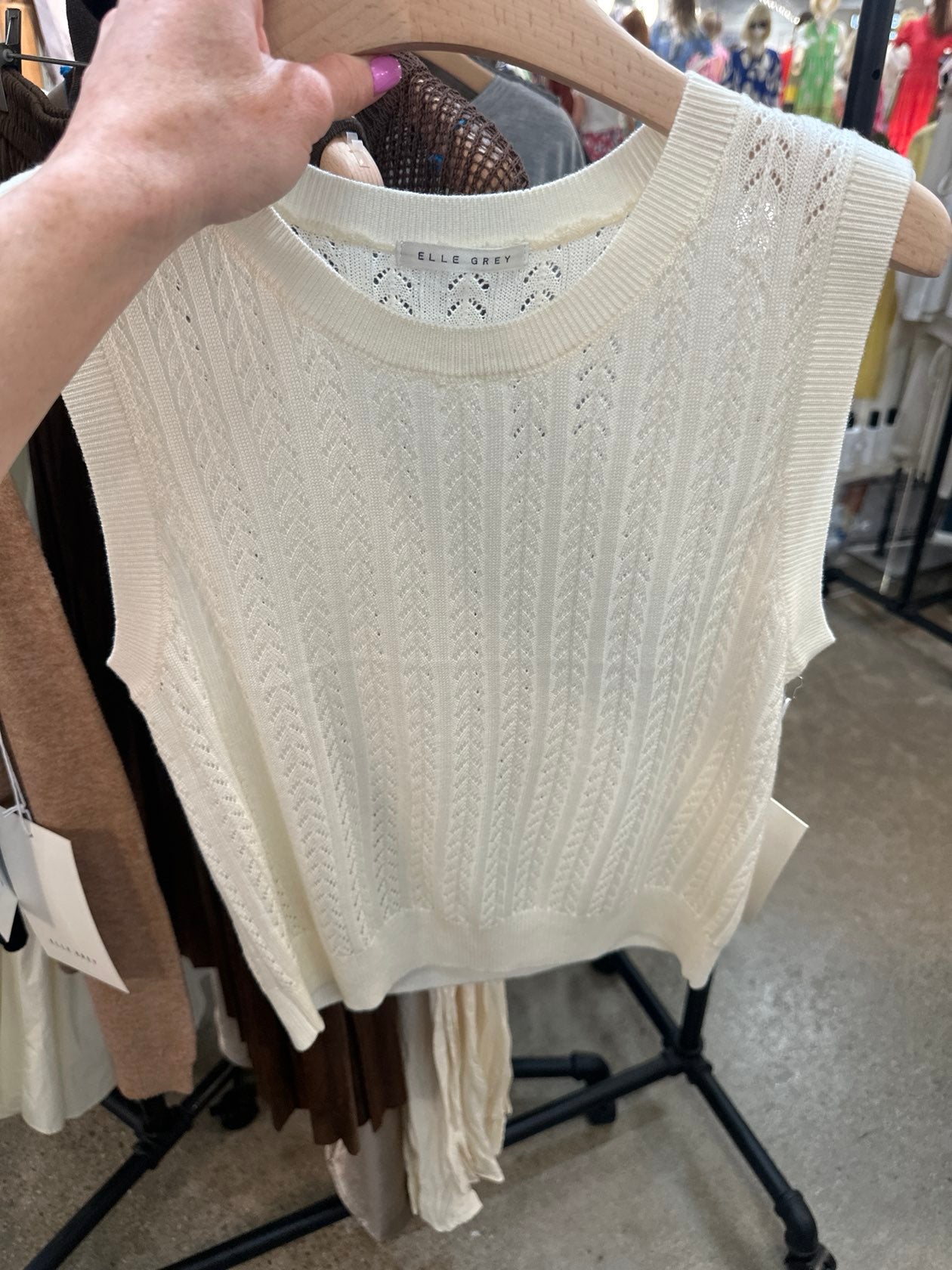 Ivory cable knit sleeveless tank top with pointelle pattern hanging on wooden hanger