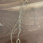 Gold tone layered chain necklace with horseshoe pendant charms on wood surface