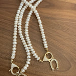 Two cream pearl necklaces with gold crystal toggle clasps on wood surface