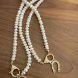Two cream pearl necklaces with gold crystal toggle clasps on wood surface