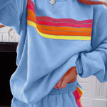 Woman wearing light blue loungewear shorts with rainbow striped side detail and matching hoodie