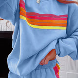 Woman wearing light blue loungewear shorts with rainbow striped side detail and matching hoodie