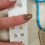 Gold horseshoe stud earrings with crystal details displayed on white card