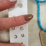 Gold horseshoe stud earrings with crystal details displayed on white card