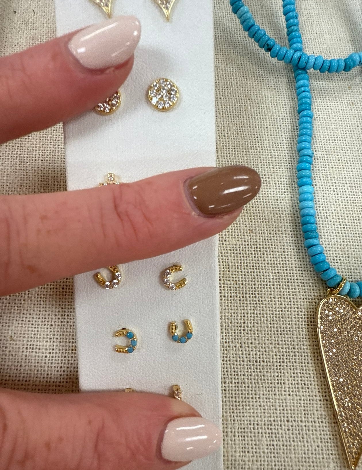 Gold horseshoe stud earrings with crystal details displayed on white card