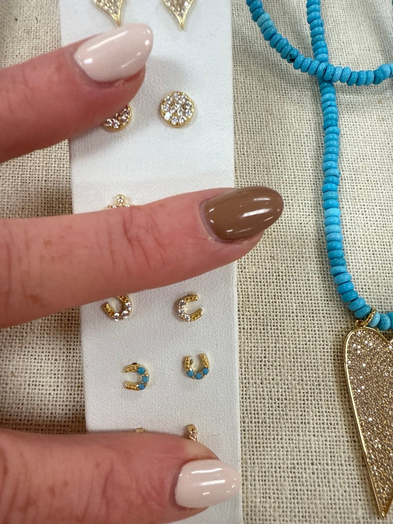 Gold horseshoe stud earrings with crystal details displayed on white card