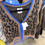 Cropped leopard print knit sweater vest with cobalt blue trim and tie neckline on hanger