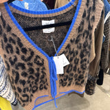 Cropped leopard print knit sweater vest with cobalt blue trim and tie neckline on hanger