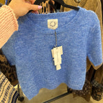 Cropped periwinkle blue wool knit top with scalloped hem and short sleeves on hanger