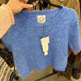 Cropped periwinkle blue wool knit top with scalloped hem and short sleeves on hanger