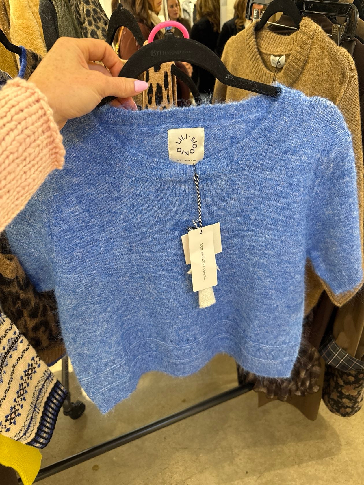 Cropped periwinkle blue wool knit top with scalloped hem and short sleeves on hanger