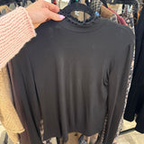Black long sleeve mock turtleneck top with ruffle lettuce edge neckline on a hanger