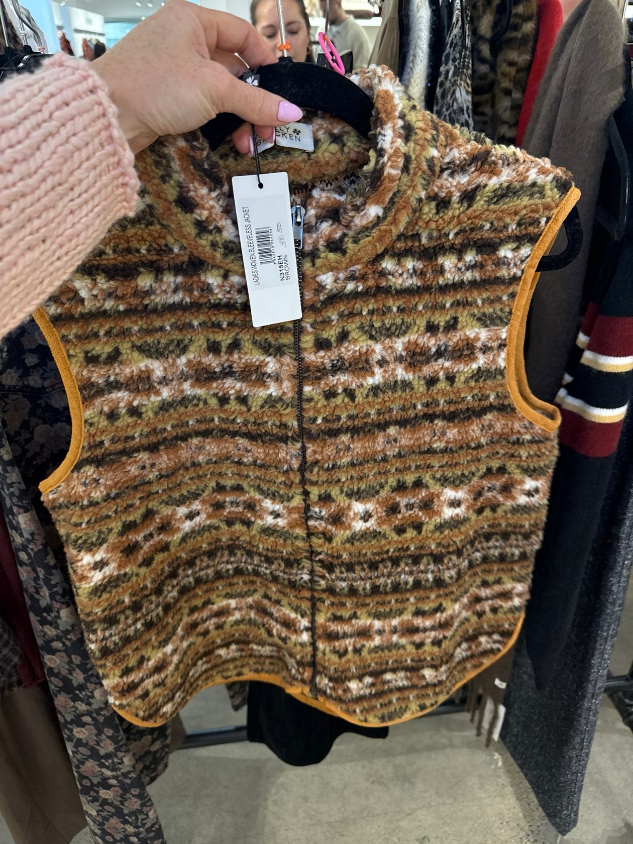 Cropped earth-tone animal print sherpa vest with zip front and mustard contrast trim on hanger